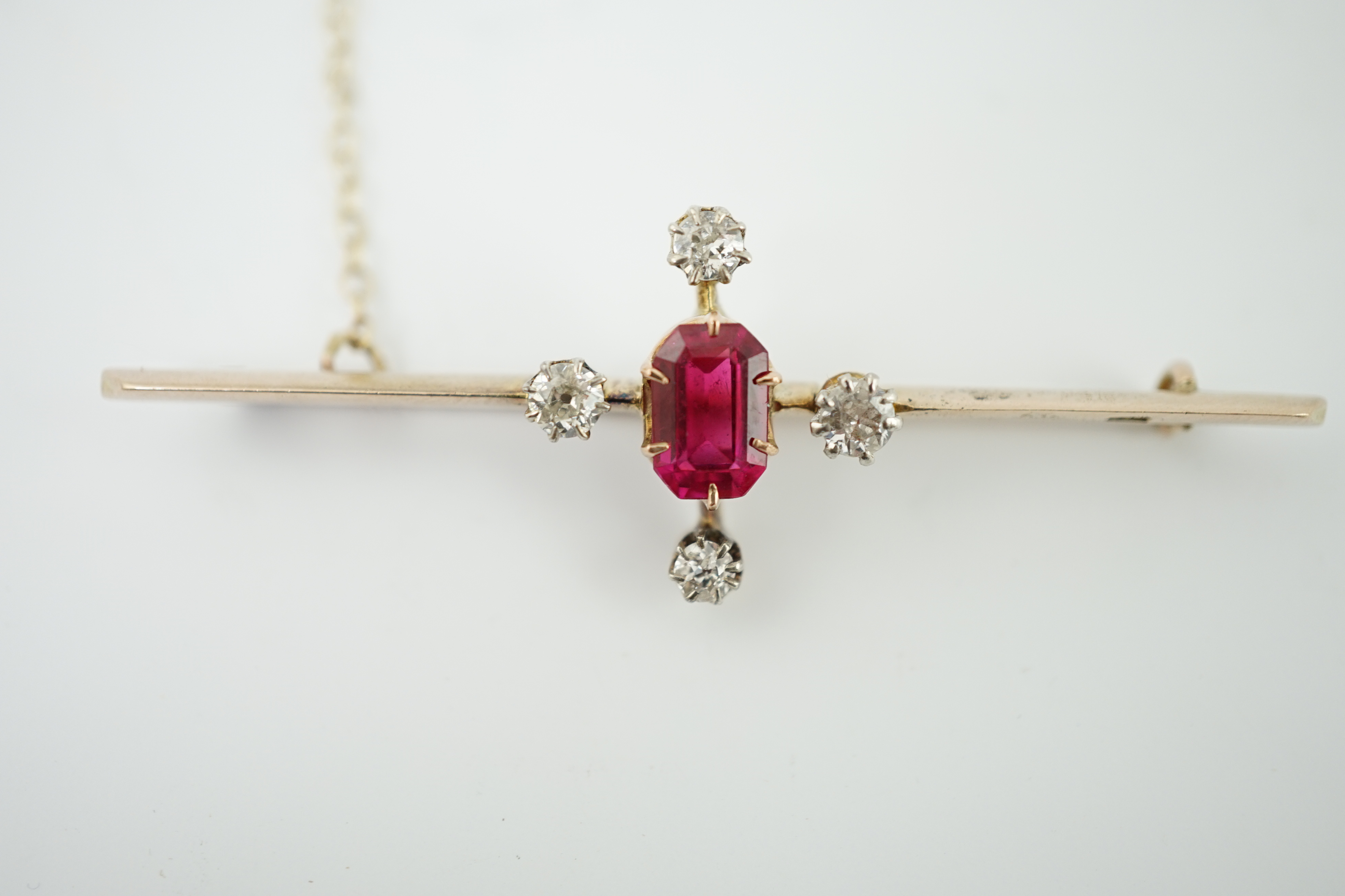 An early to mid 20th century gold, single stone oval cut synthetic ruby and four stone round cut diamond set bar brooch, 57mm, gross weight 4.6 grams. Condition - good